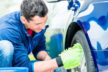 Worker using microfiber car wash mitt for cleaning rim