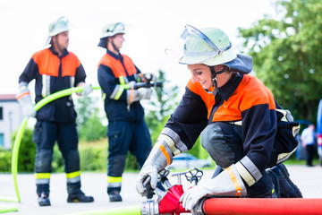 Naklejka premium Feuerwehrfrauen löschen mit Schlauch