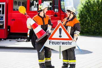 Feuerwehrfrauen stellen beim Notfalleinsatz ein Warnschild auf