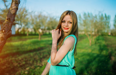 Woman in a beautiful long turqoise dress posing on a meadow in t