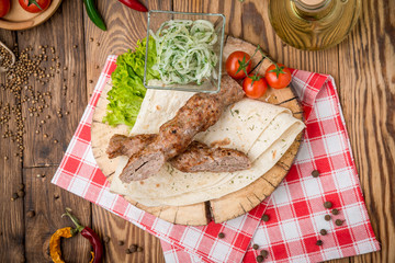 grilled beef meat on the grill kebab on pita bread and a wooden plate
