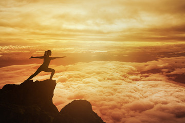 Woman meditating in yoga position on the top of mountain