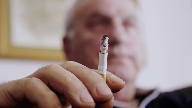 Detail of old smoker hand while hold a burning cigarette