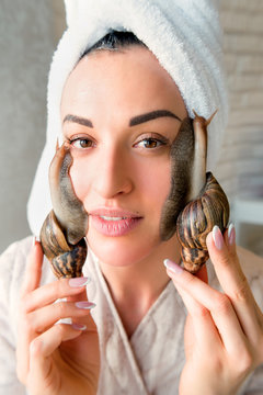 portrait of young darkhaired woman with snails achatina giant on her face