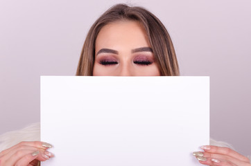 Beautiful young girl holding a paper over her mouth.