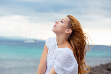 Woman relaxing at beach enjoying summer freedom with hair in the wind by the water seaside