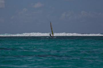 A windsurfer approaching a line of breakers in Mauritius.