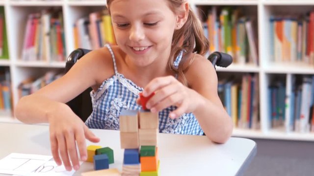 Disabled girl playing with building blocks in library