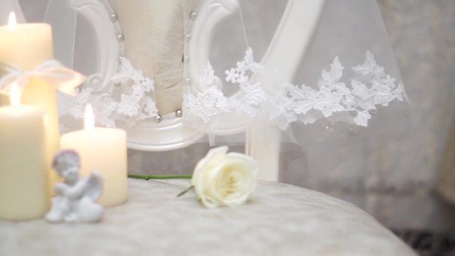 Candle, a rose and a figure of an angel on a background of the bride veils