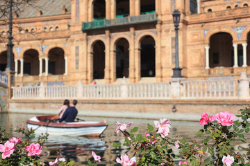 Obraz premium Roses and blurred touristic boat with loving couple, Spain square, Seville, Spain 