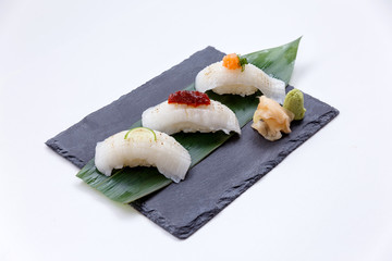 Torched Engawa Sushi Topping with Lime, Chilli Jam and Minced Daikon Served with Wasabi and Prickled Ginger on The Black Stone Plate.