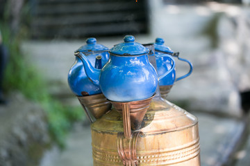 Close-up of three vintage beautiful traditional Turkish blue teapots placed above copper samovar with blurred background