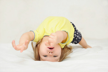 Little girl having fun lying on back spine, back bend, bridge figure, happy smiling child,...