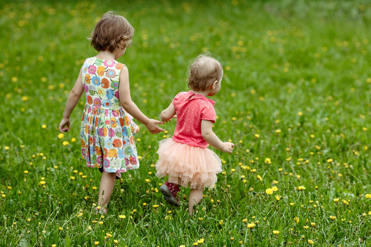 Two children going in spring green field