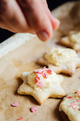 Hands of person putting colorful topping on cookies.