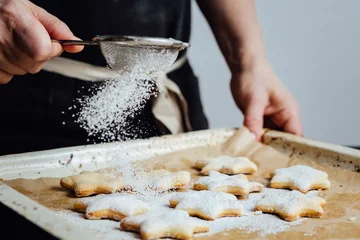 Crédence de cuisine en verre imprimé Cuisinier Hands of cook adding powdered sugar to cookies as a topping