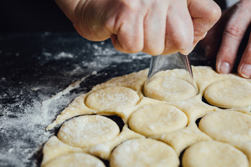 Person giving circle shape to homemade cookies with shot glass.