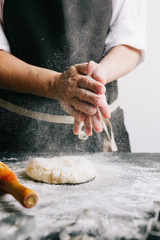 Cook covering hands with flour for beating up a cookie pastry. Vertical studio shot.