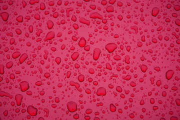 Droplets of rain on a red metallic background