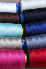 Group of bobbins of thread of various colors on a wooden table
