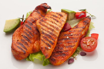 Grilled chicken fillet with green salad, tomato and avocado, on white background