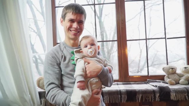 Happy father with his young son in the arms of a winter window