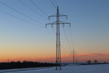 Winter landscape with fields and meadows / Sunset in the winter / High-voltage masts.