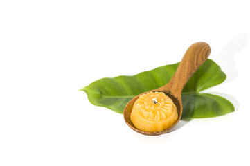Sweet yellow desert royal Thai cuisine decorated with green leaf and wooden spoon on solid white background