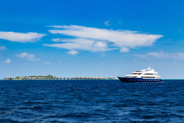 Fototapeta na wymiar Luxury yacht in ocean near resort island with bungalows