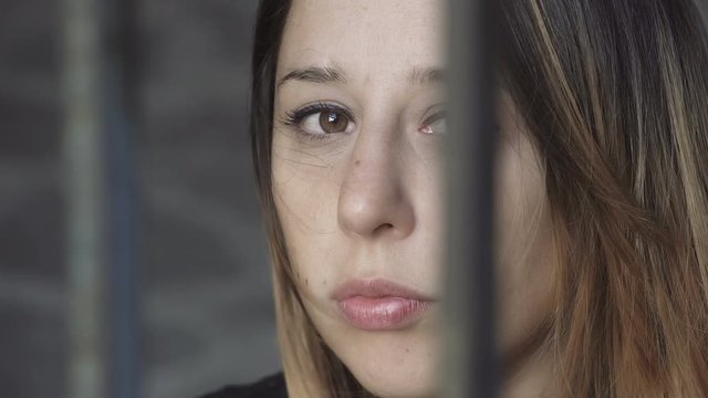  sad young woman trapped behind bars