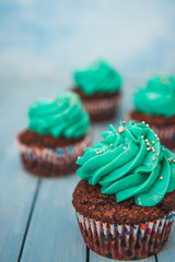 Chocolate cupcakes with cream on blue background