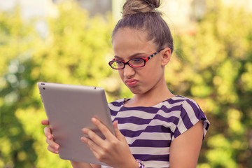 Upset sad skeptical unhappy serious girl using mobile pad computer