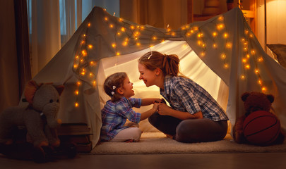 happy mother and daughter playing at home in tent . - Powered by Adobe