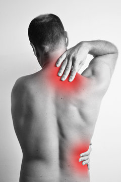 Caucasion man having back ache problems. Concept with red dots highliting the problematic area. Studio photograph.
