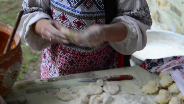 The process of preparation of Ukrainian traditional bakery products - dumplings. Women's hands knead the dough. Rustic style.