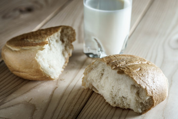 Milk in a glass jug. Bread on wooden background. Bio products. Food.