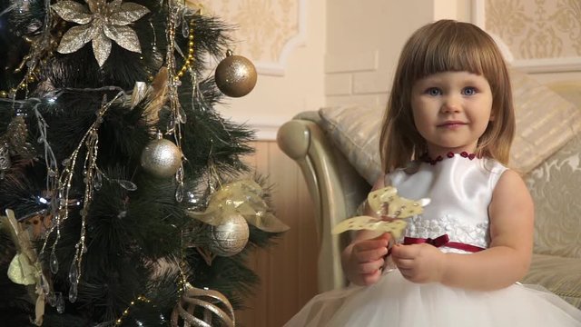 Little girl in festive dress with a golden butterfly near the Christmas tree