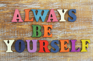 Always be yourself written with colorful wooden letters on rustic surface
