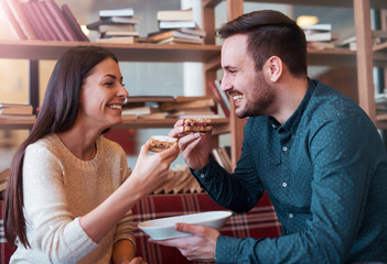 Couple in love. Young couple eating cake surrounded with books i