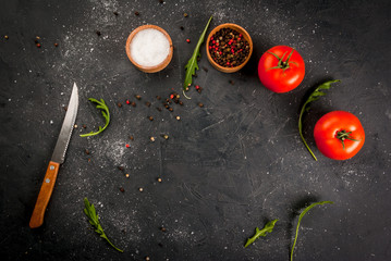 Dark gray stone (concrete) kitchen table with a knife, spices, herbs and vegetables. cooking background. Top view, copy space