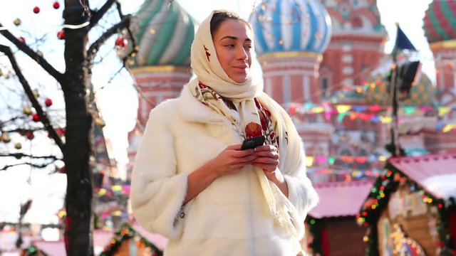 Young beautiful woman reads the message on a cell phone on Red Square, Moscow, Russia