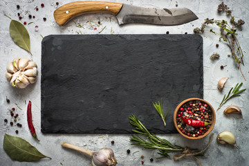Black slate board, herbs and spices. Food ingredients background.