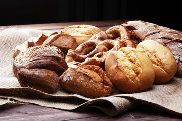 Different kinds of bread and bread rolls on board from above. Kitchen or bakery poster design.
