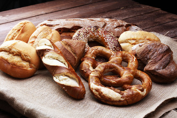 Different kinds of bread and bread rolls on board from above. Kitchen or bakery poster design.