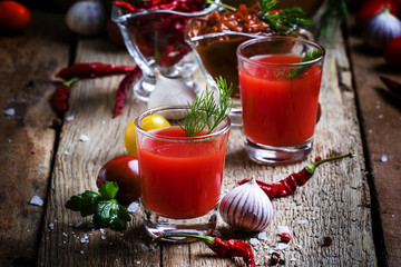 Spicy tomato juice with vegetables on a vintage wooden backgroun