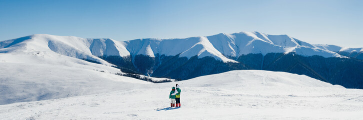 A guy and a girl traveling in winter mountains. Panorama of Carp