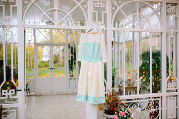 white wedding dress hanging on the door of the greenhouse