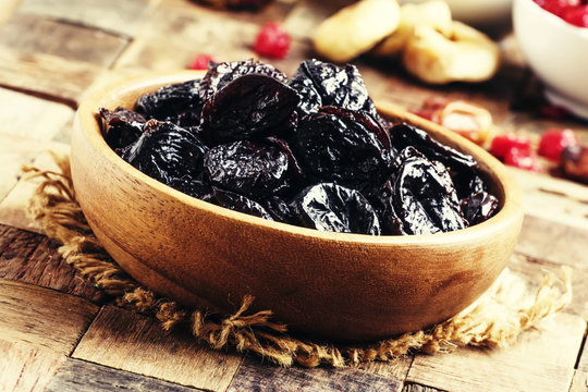 Dried Sweet Prunes Or Dark Plums In Bowl On Wooden Background, S