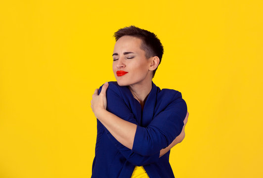 Closeup portrait confident smiling business woman holding hugging herself yellow wall background. Positive human emotion, facial expression, feeling, reaction situation attitude. Love yourself concept