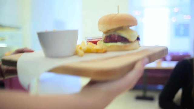 Girl waiter delivers the burger.